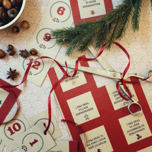 Bilde av lapper til julekalender med nummer og aktiviteter på et bord med granbar og julepynt